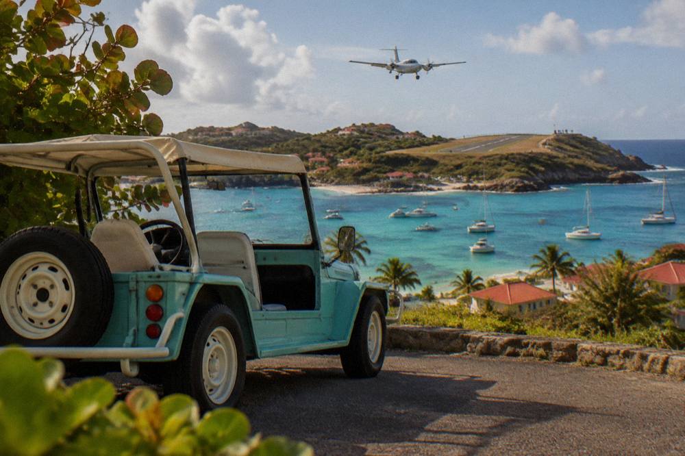 An open-air Mini Moke parked on a narrow road above a Caribbean bay