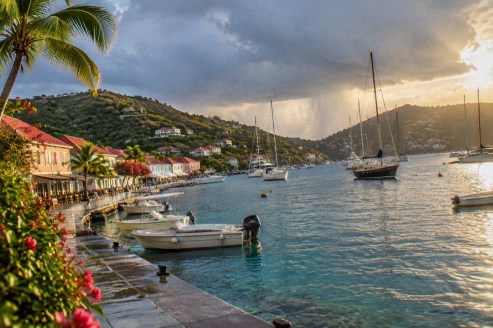 Sailing yachts moored in a small harbor surrounded by hills at golden hour