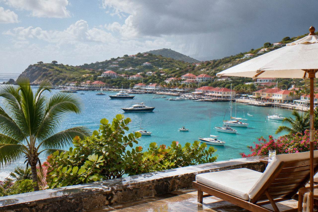 A resort terrace above a turquoise bay on a Caribbean island with green hills