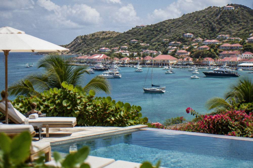 A small hotel pool deck overlooking a calm Caribbean bay at midday