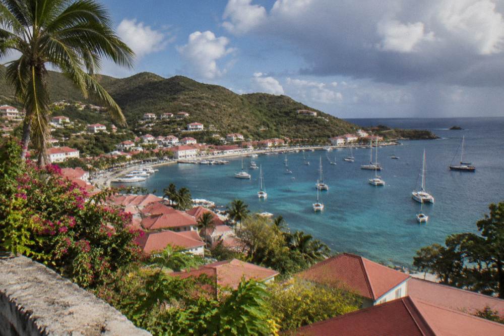 A hillside view over red rooftops and sailboats anchored in a Caribbean harbour
