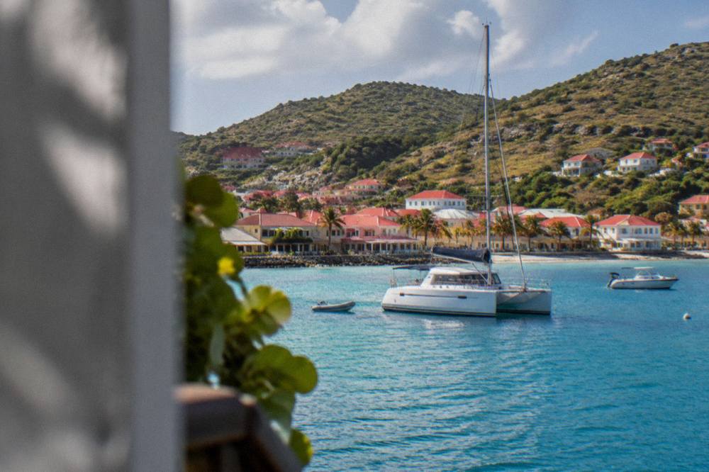 A catamaran at anchor in a quiet Caribbean bay with green hills behind