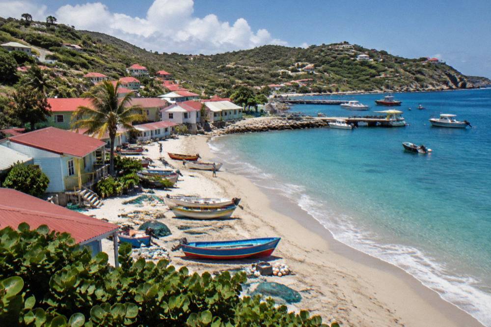 A small Caribbean fishing village with colorful wooden boats on a sandy shore