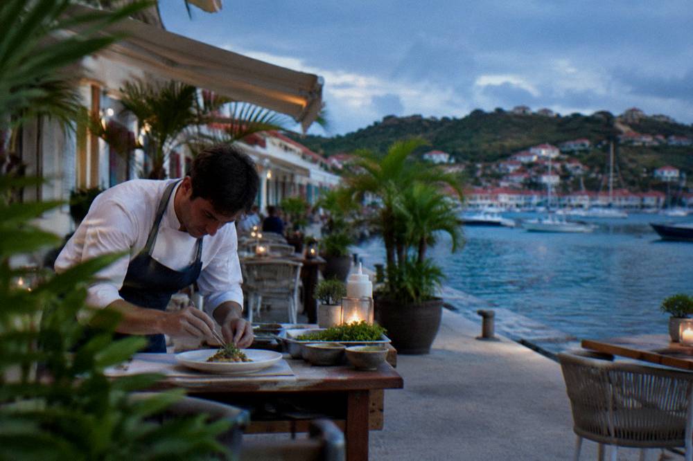 A chef plating a refined dish on a white ceramic plate