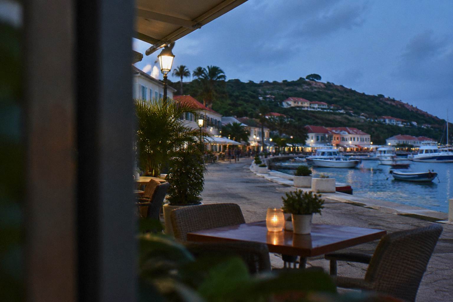 Restaurant table set on a terrace in evening light, chairs empty