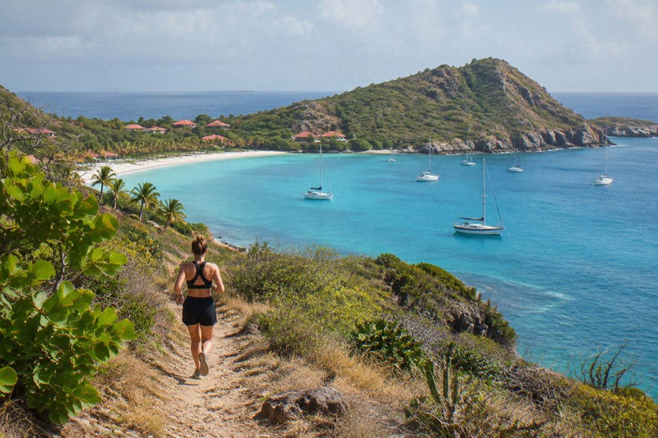 Sailboats anchored in turquoise water below the hills of a Caribbean island