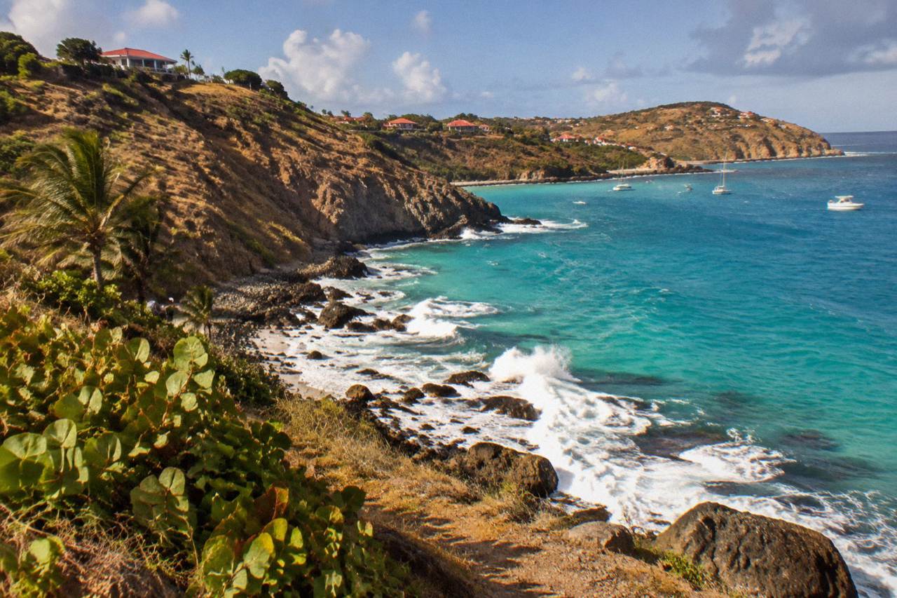 A curve of turquoise Caribbean water on a hillside island coastline