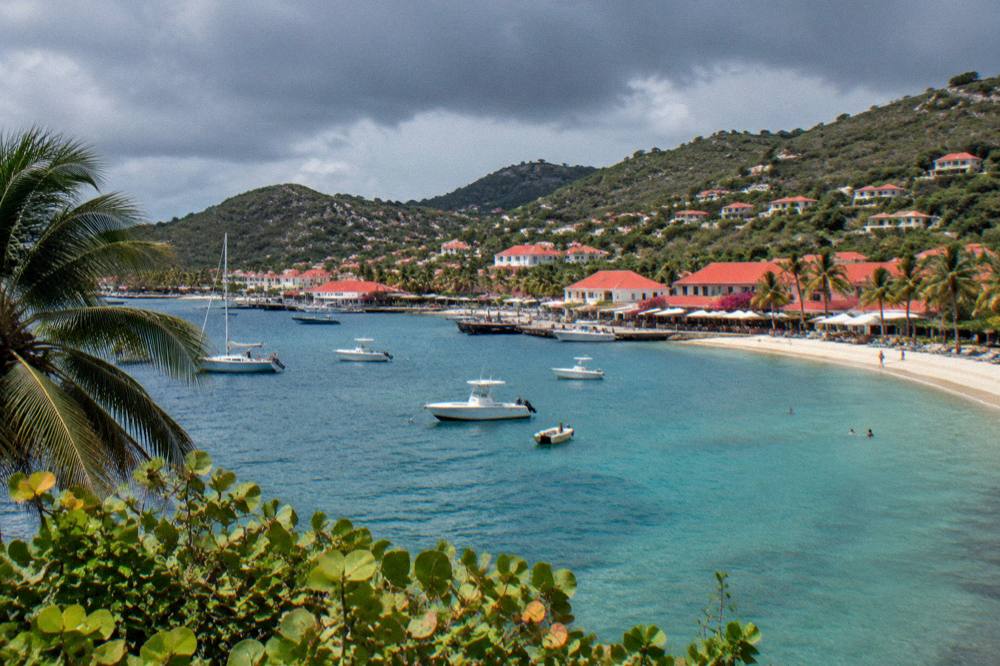 Dark rain clouds over green hills above a Caribbean coastline