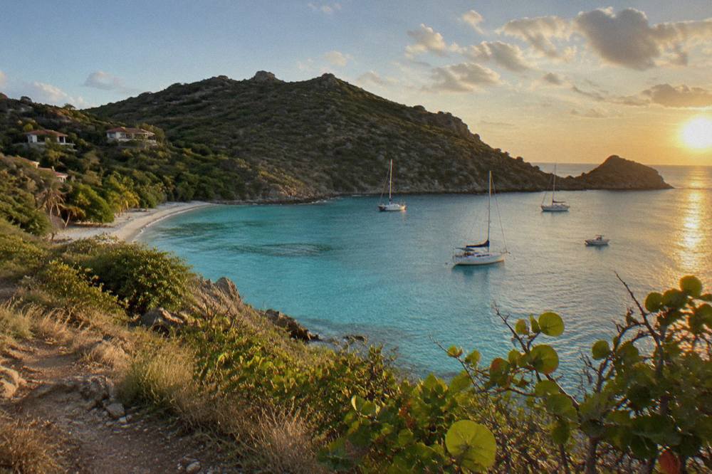 A secluded bay with clear shallow water framed by green hills