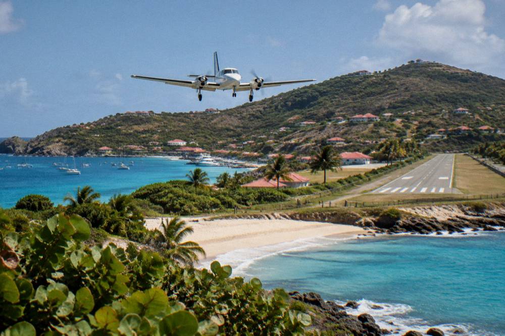 A small turboprop aircraft on a short runway beside a beach