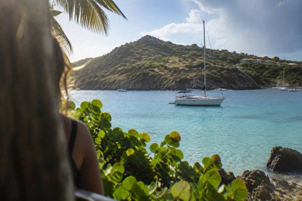 A boat anchored in clear blue water with a green hillside behind it