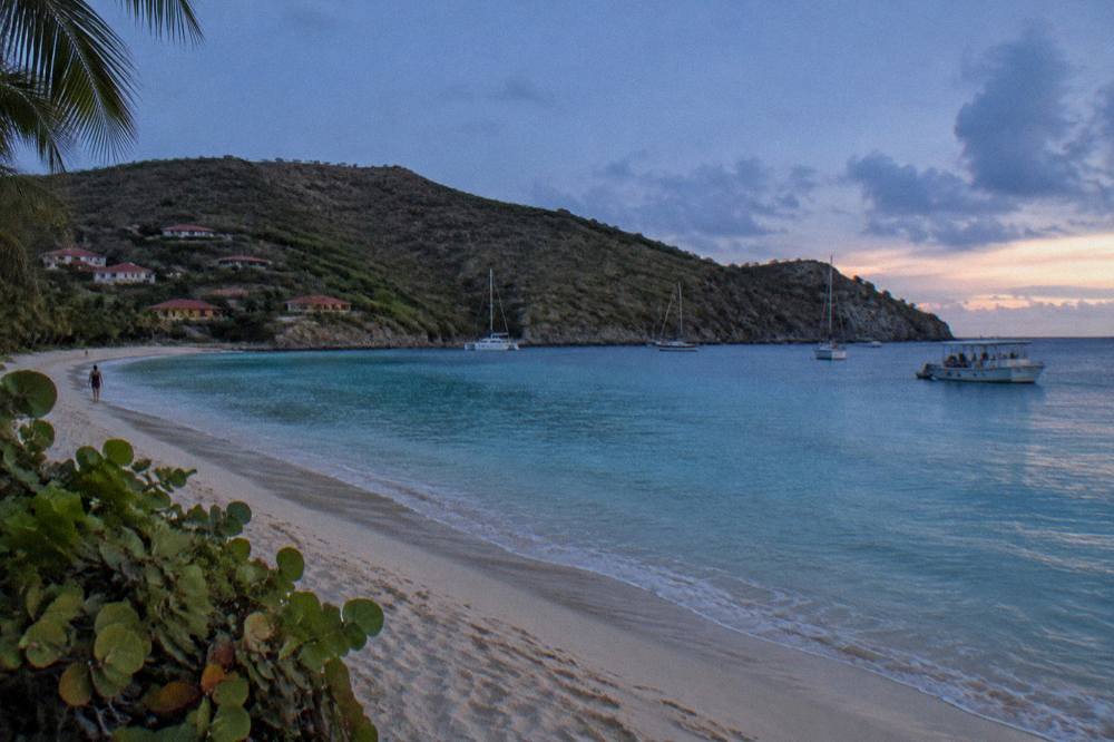 A calm turquoise bay with a wooded headland and a snorkel boat at anchor