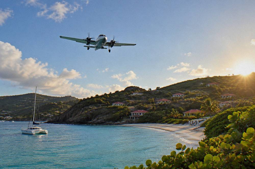 A charter boat anchored in a calm bay with wooded hills in St Barts behind it