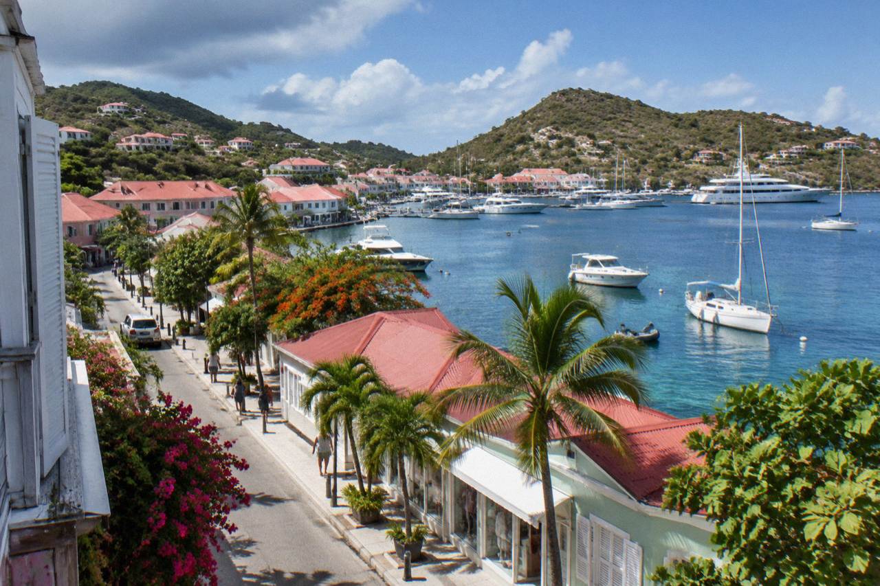 Boutique storefronts along a harbor street in Gustavia with yachts moored in the background