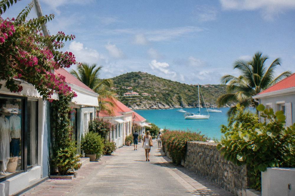 Sailing boat anchored in a turquoise bay with a wooded hill behind