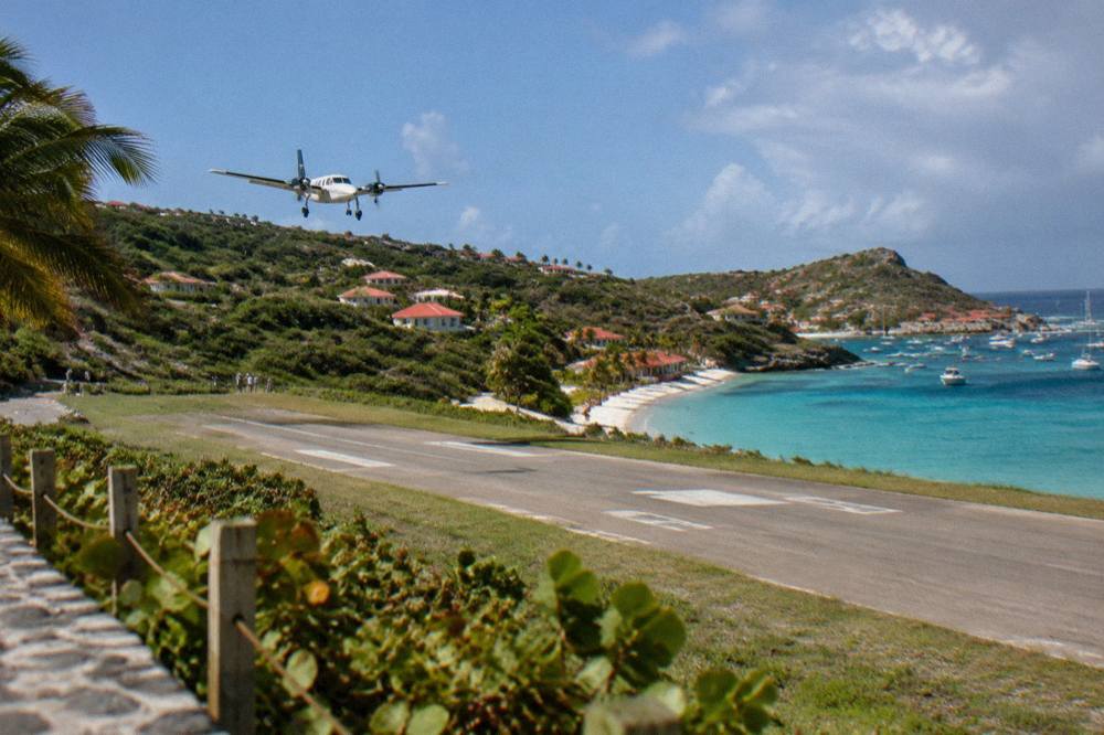 Small turboprop aircraft on a short runway beside a beach