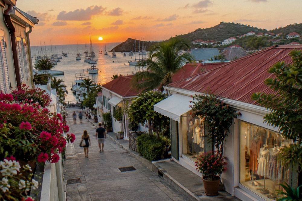 Sunset over a Caribbean harbor with masts silhouetted against an orange sky