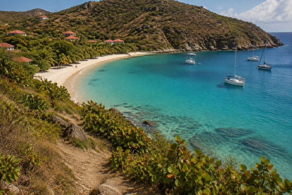 An empty curve of white sand at Colombier Beach in St Barts seen from a hillside path