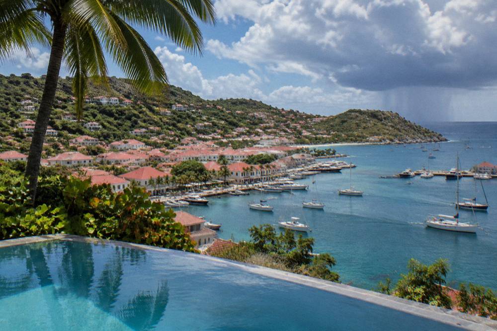 Palm trees and a still infinity pool under a partly cloudy tropical sky