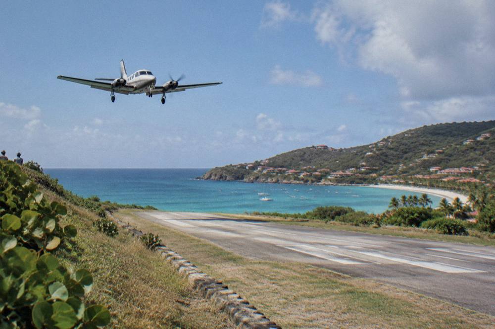 Small turboprop aircraft on the runway at Gustaf III Airport in St Barts with the beach beyond