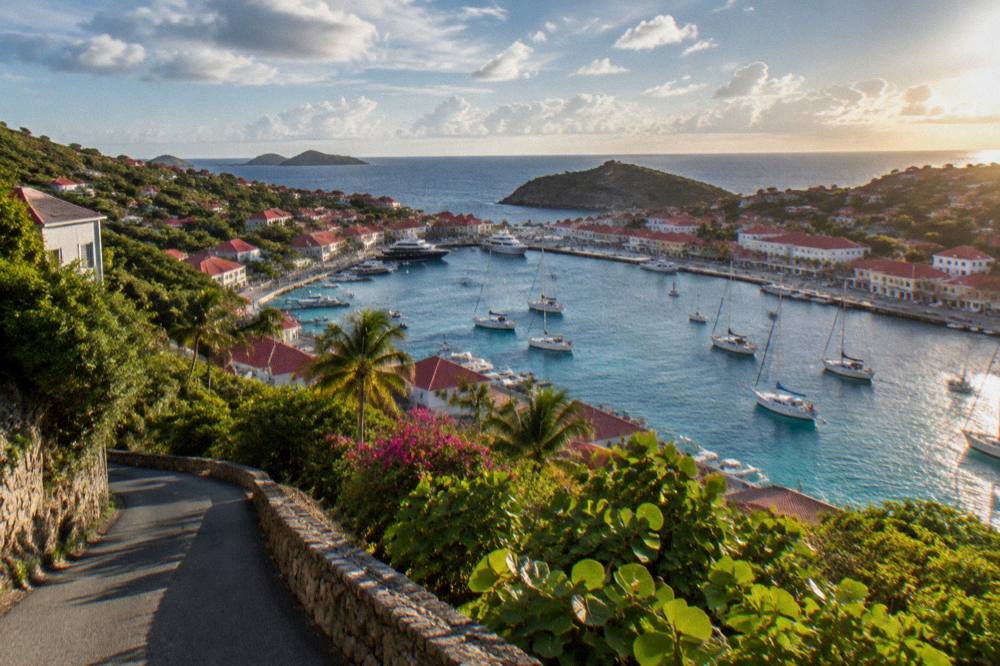 Narrow hillside road in St Barts winding between green slopes above the sea
