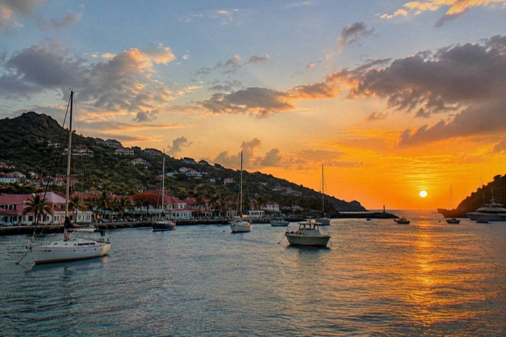 Sunset over the harbor of Gustavia in St Barts with boats silhouetted against an orange sky
