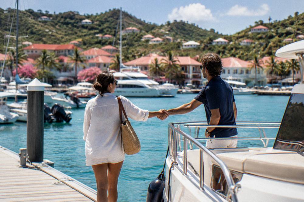 Two people shaking hands over the rail of a boat at a marina dock in late afternoon light