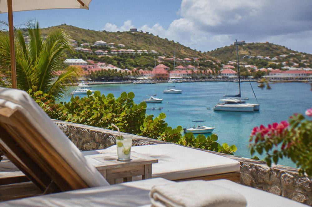 A quiet hotel terrace with white loungers facing turquoise Caribbean water