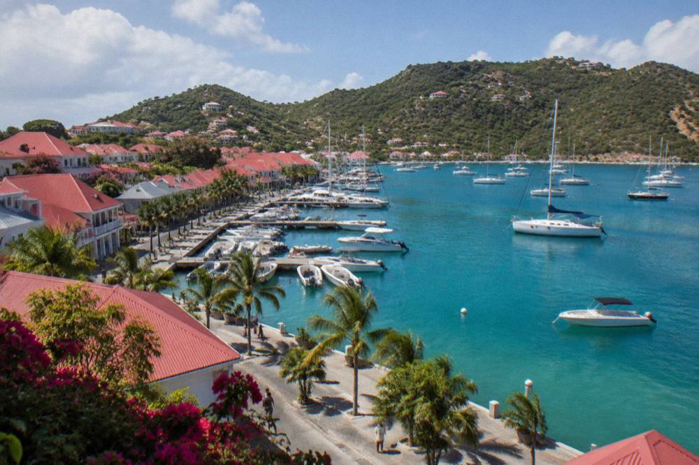 Sailboats anchored in a green bay on St Barts with wooded hills behind