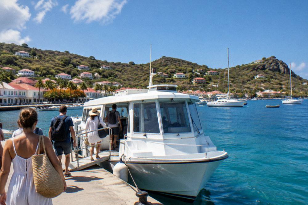 Passengers boarding a small white ferry at a Caribbean marina dock
