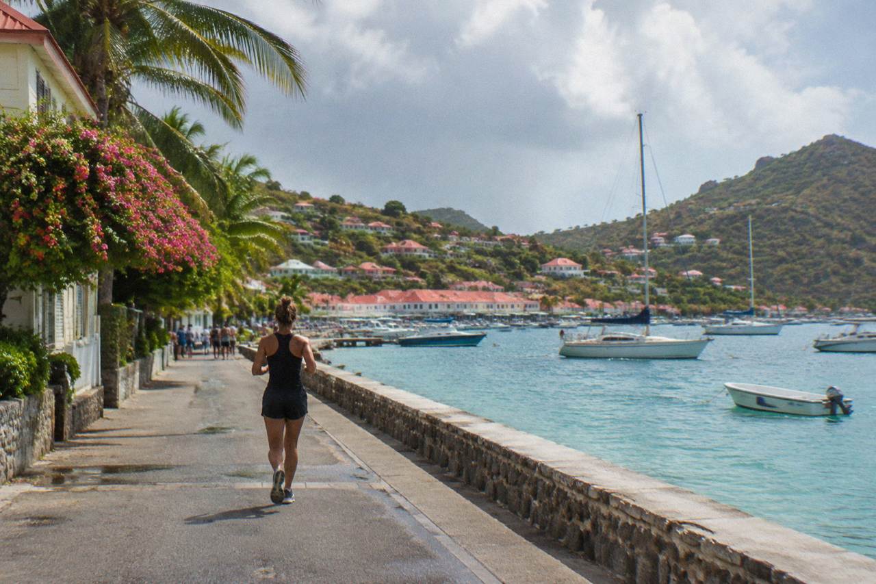 Sailboats anchored in turquoise water below the hills of a small Caribbean island
