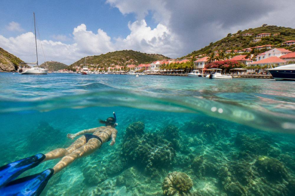 A snorkeller swimming above a coral reef in clear shallow water