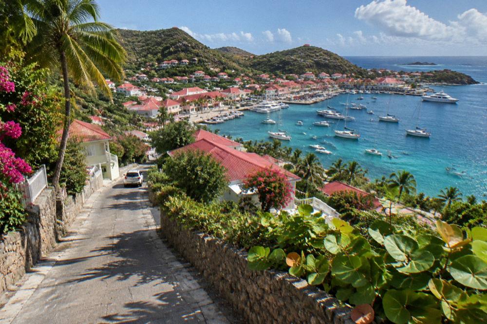 A narrow steep road winding between villas and green hills in St Barts