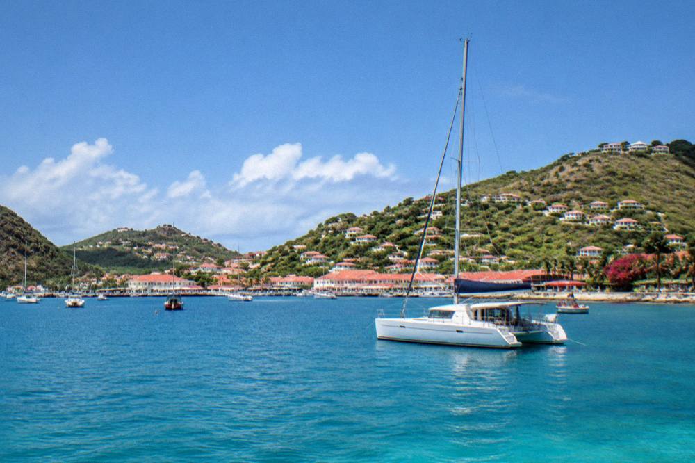 A catamaran at anchor in a quiet bay at sunset near St Barts