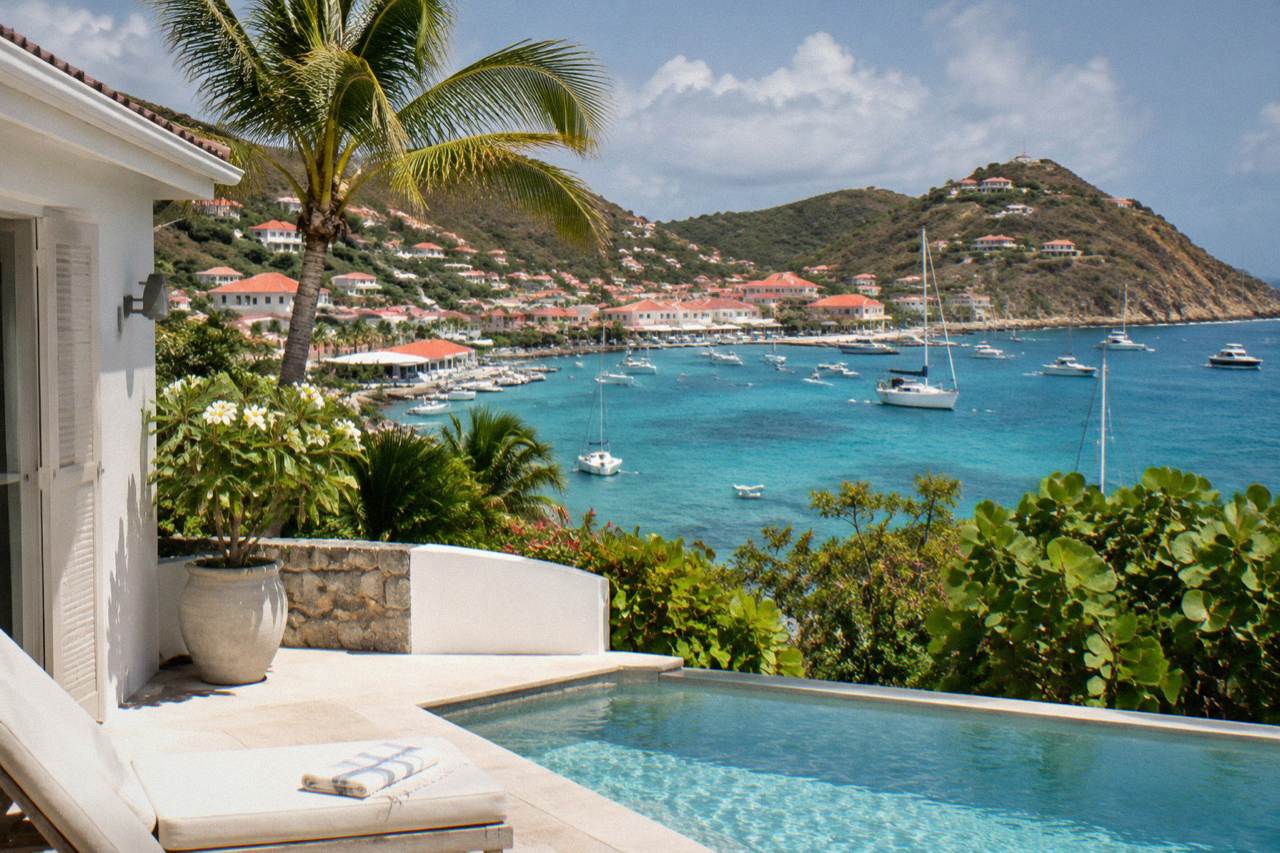 A white-walled villa with a pool terrace overlooking a turquoise Caribbean bay