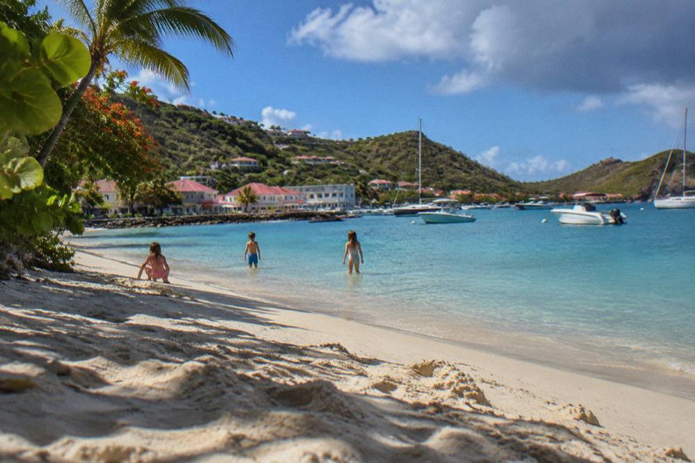 Children playing on a quiet white sand beach beside calm shallow water