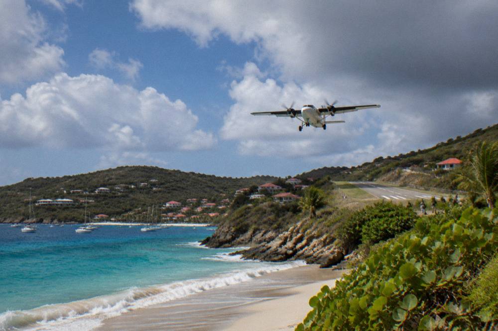 A small twin-engine turboprop aircraft on a short runway beside a beach