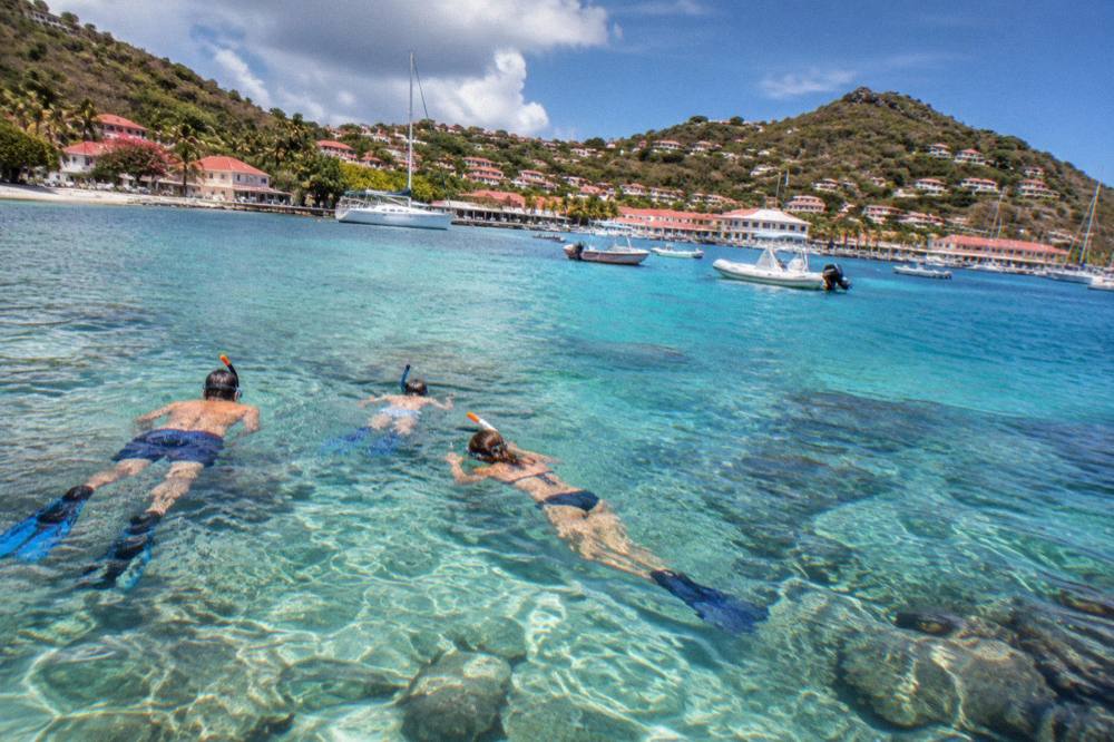 A family snorkelling over clear shallow water above a coral reef