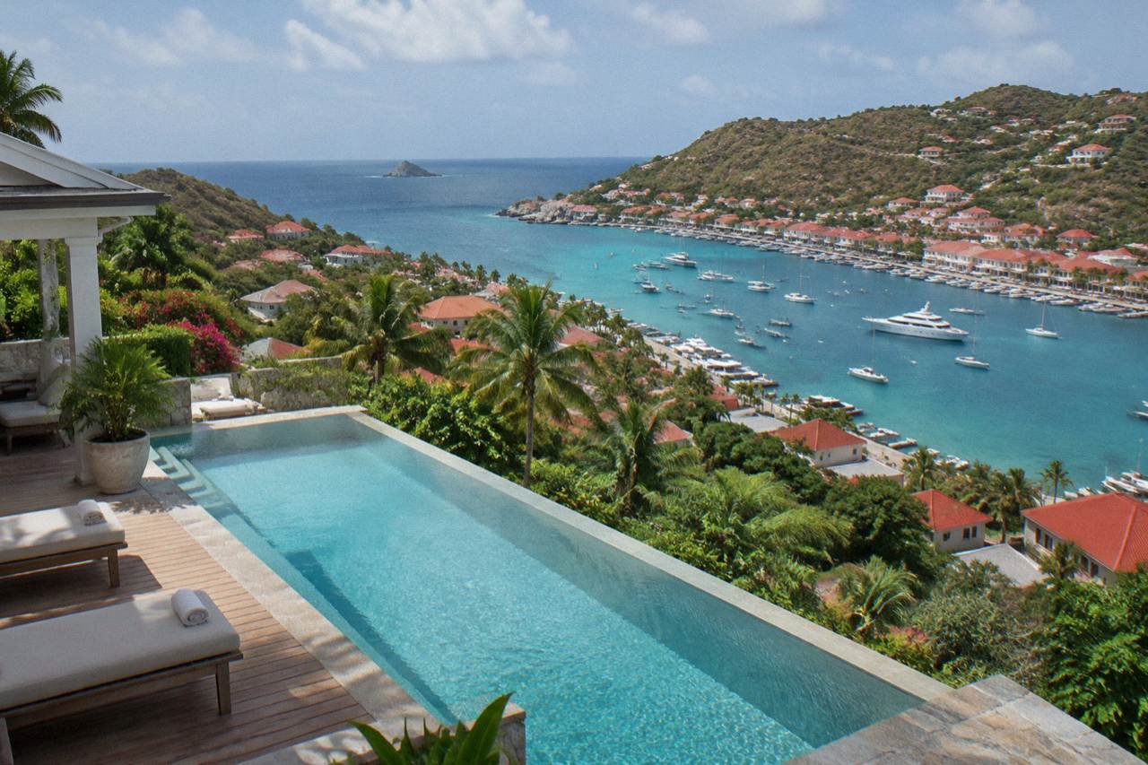 A hillside villa terrace in St Barts with a long pool and lounge chairs facing the Caribbean sea