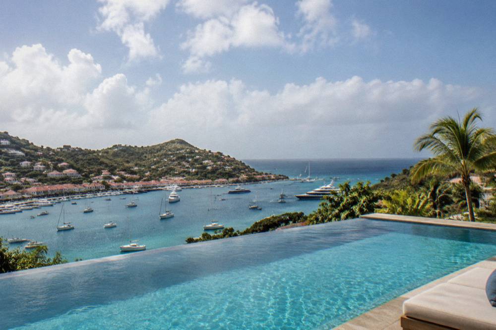 An infinity pool at a St Barts villa overlooking green hills and the ocean