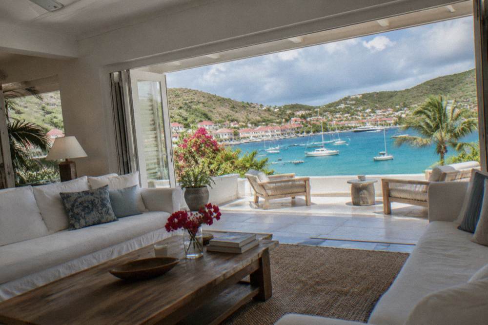 A spacious villa living room in St Barts with white sofas and open doors to a terrace