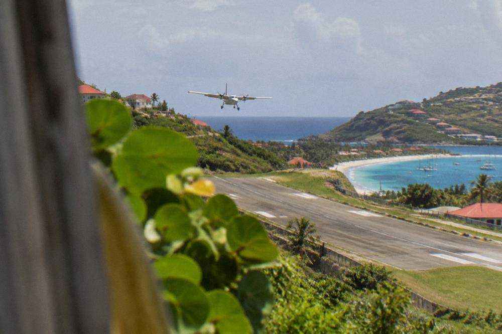 A small turboprop aircraft on the short runway at Gustaf III airport in St Barts
