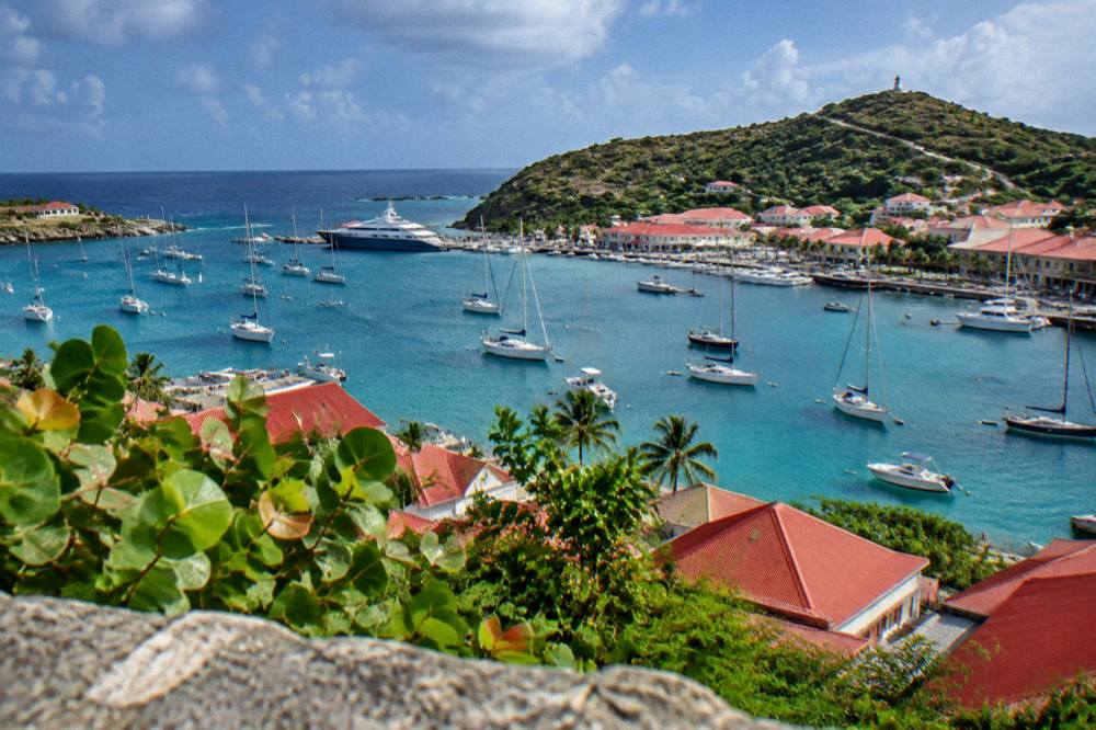 A wide view over red roofs and sailboats in Gustavia harbour from a hillside in St Barts