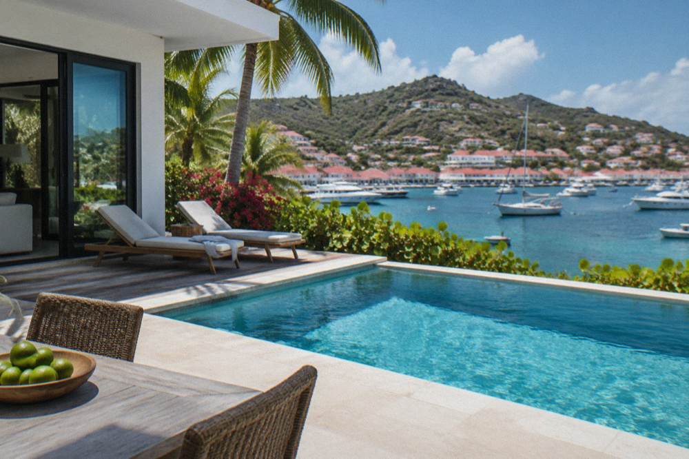 A modern villa interior opening through glass doors onto a pool deck