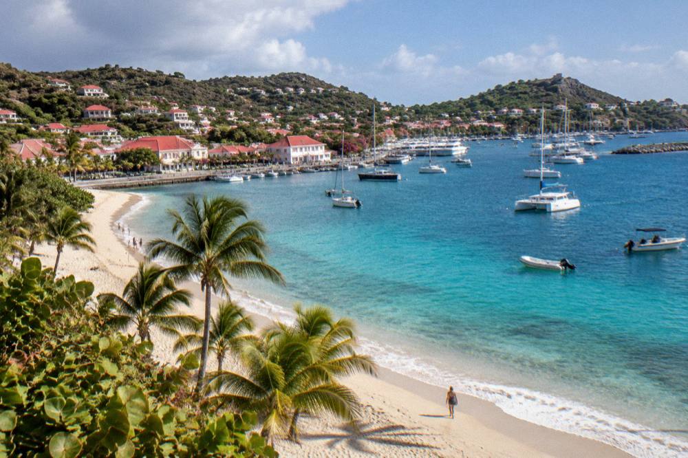 A wide sandy beach with palm trees and few people on the south coast of St Barts