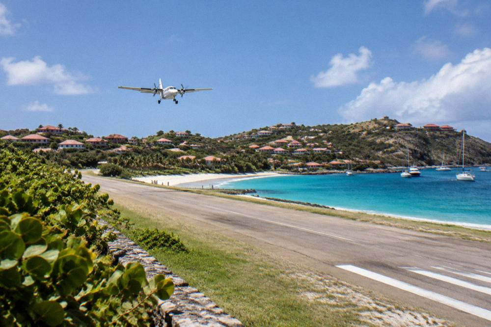 A small turboprop aircraft on a short runway by the sea at Gustaf III Airport