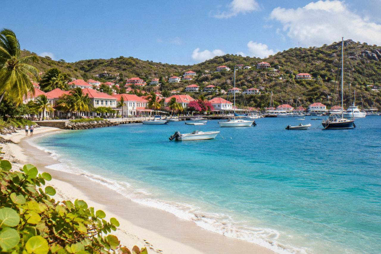 Turquoise water lapping a white sand beach on St Barts under a bright sky