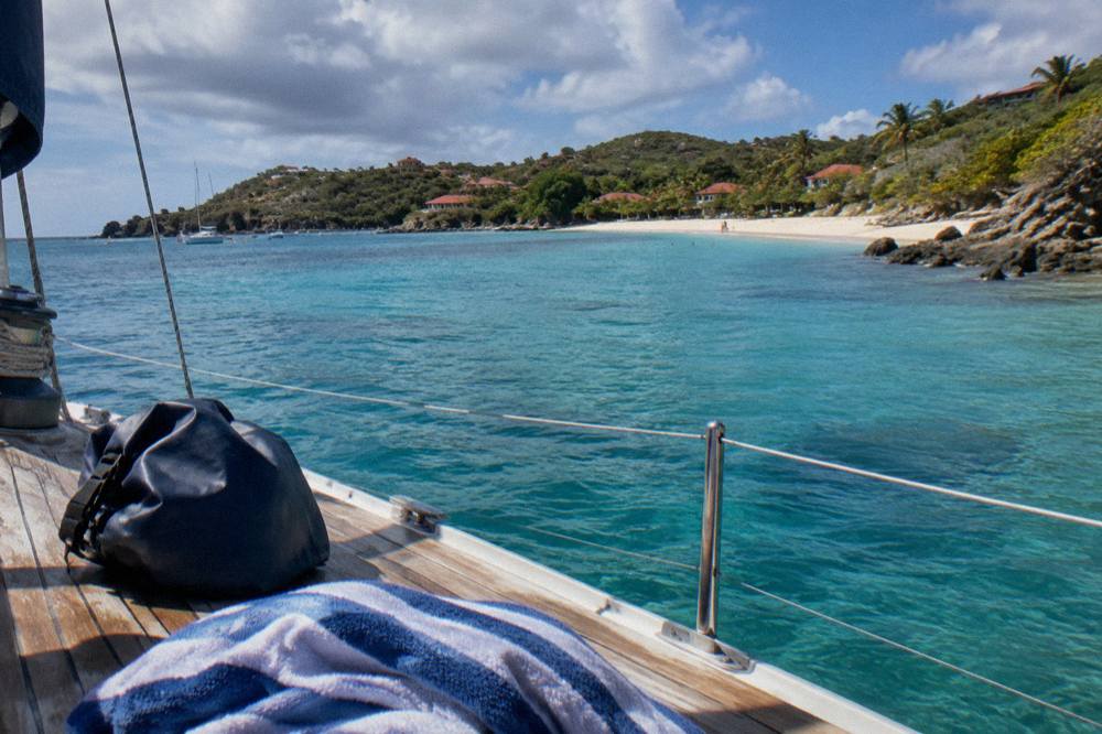 A dry bag and towel resting on the wooden deck of a small sailing boat