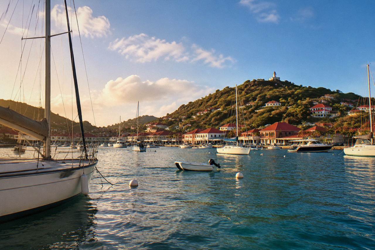 View over Gustavia harbor with boats at anchor and red rooftops under a blue sky