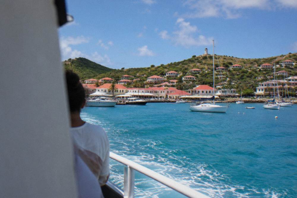 Passenger ferry approaching a small Caribbean harbor town with hills behind